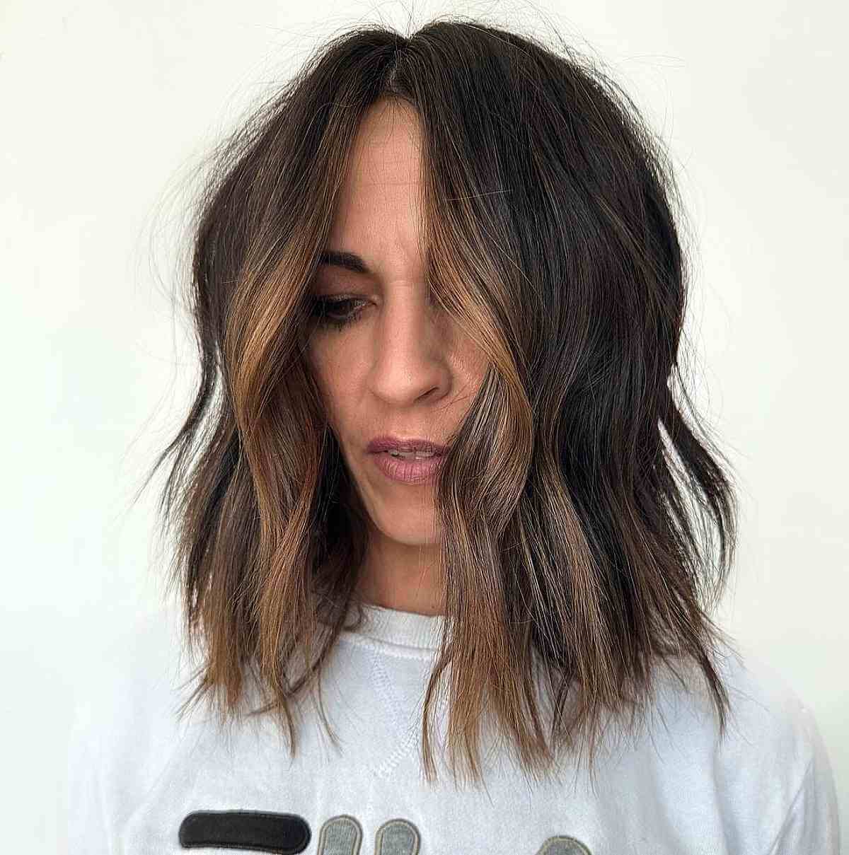 modern choppy lob with a light brown money piece