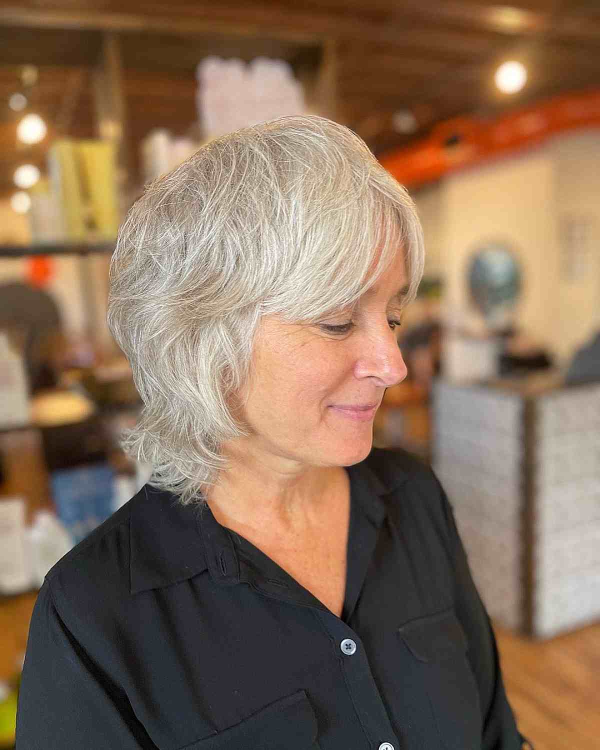 a 60 year old with short layered waves with curtain bangs on white hair