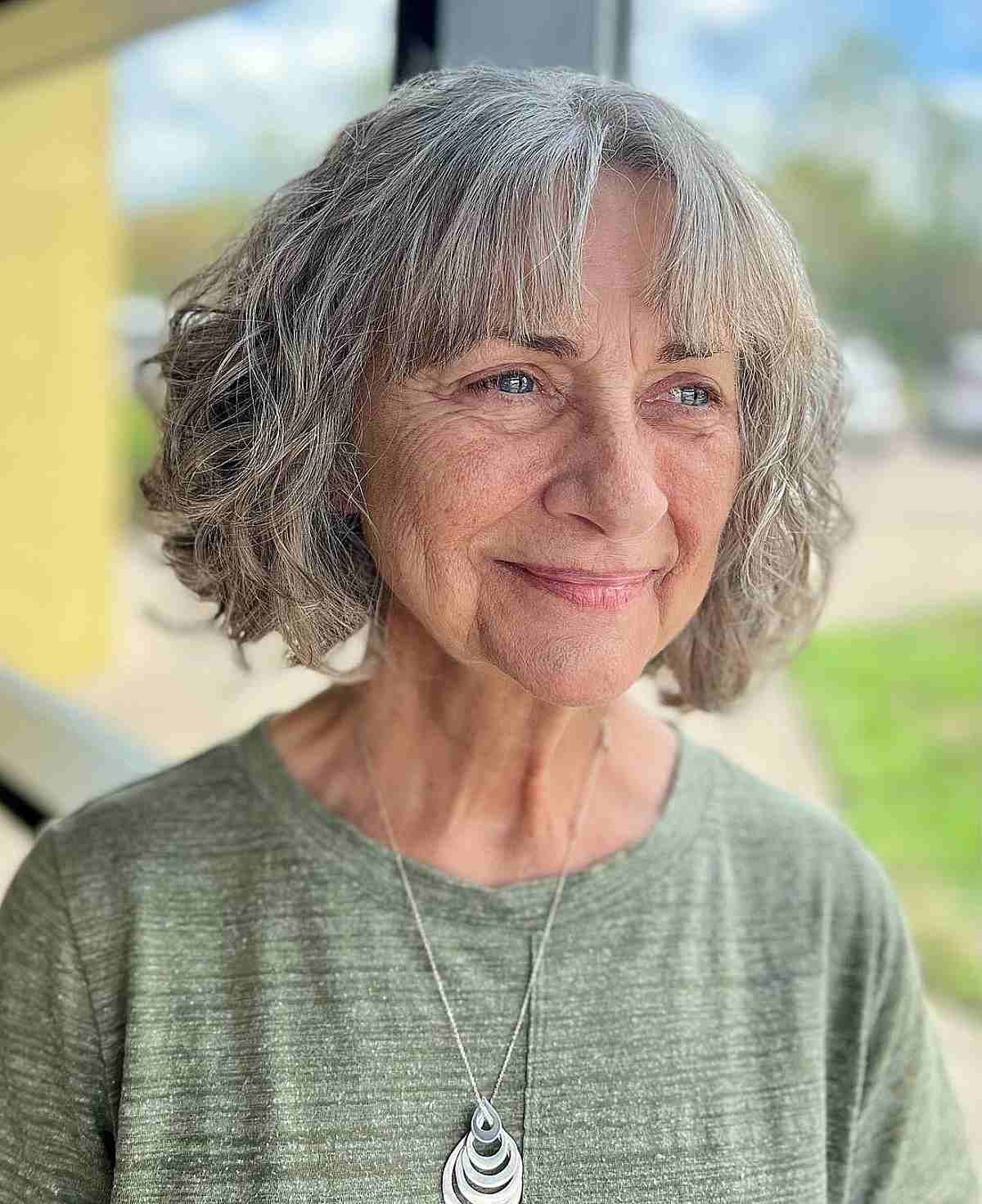 center parted curly bob with curtain bangs for women 60 and up