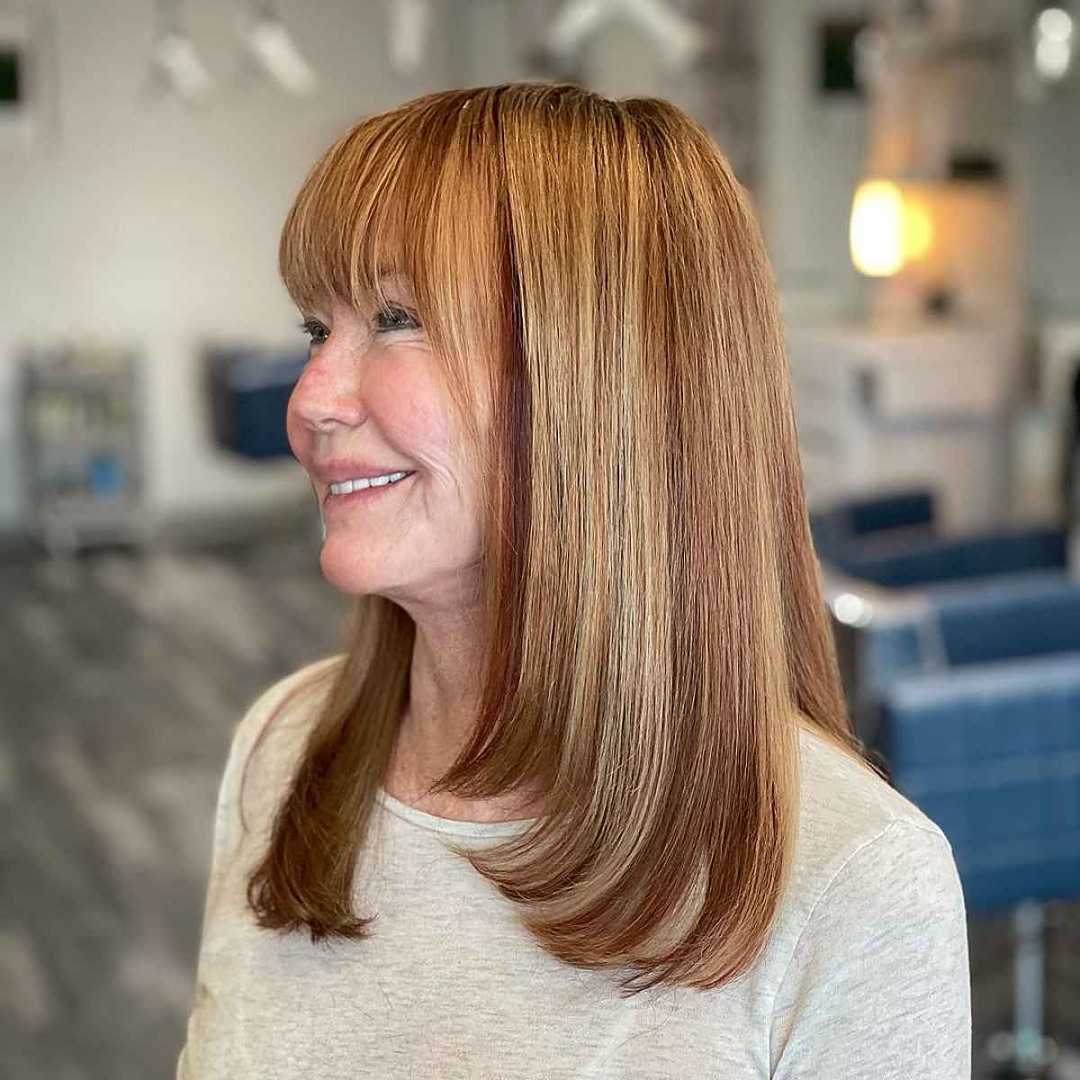 collarbone length cut with bangs and dark auburn lowlights for women over sixty