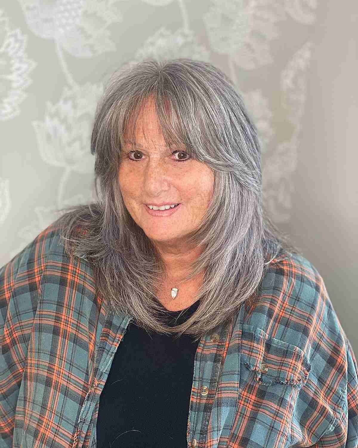 light feathered curtain bangs and razored layers on grey hair for a woman over 60