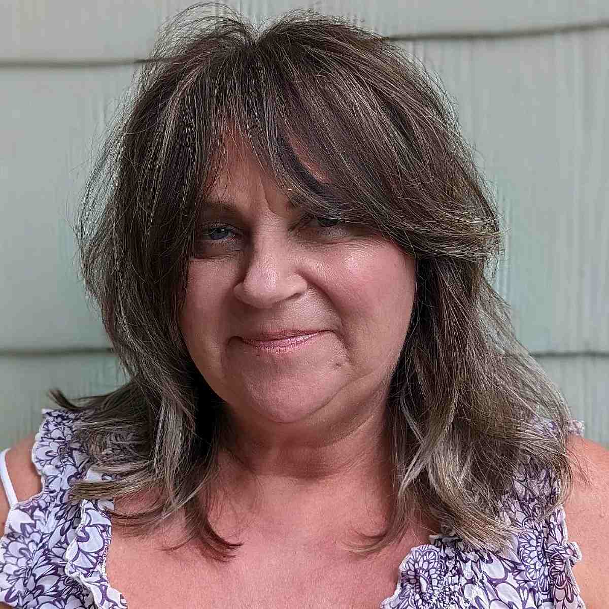 textured mid length hair with long curtain bangs for women past 60