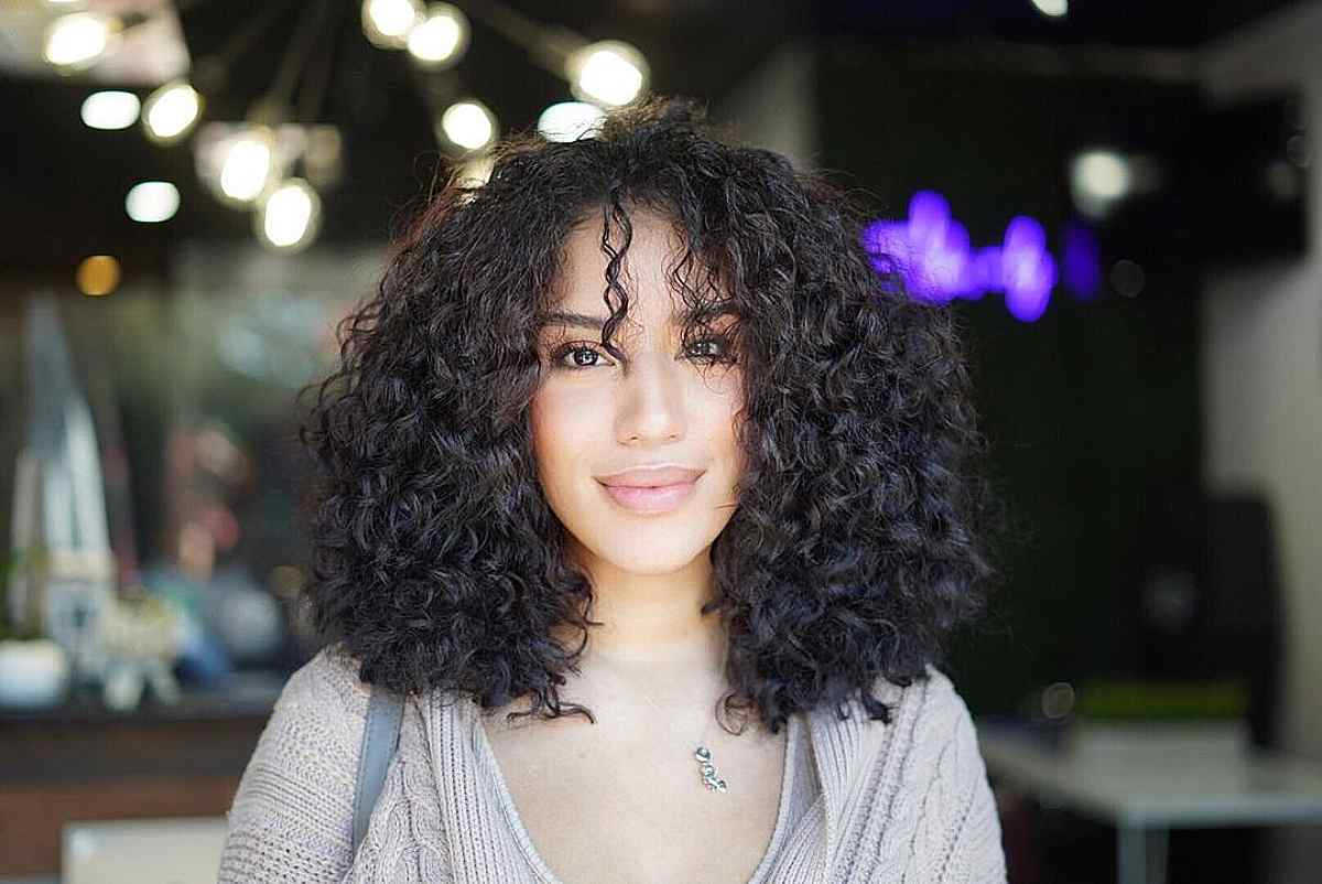 medium kinky haircut with piecey bangs for oval faces