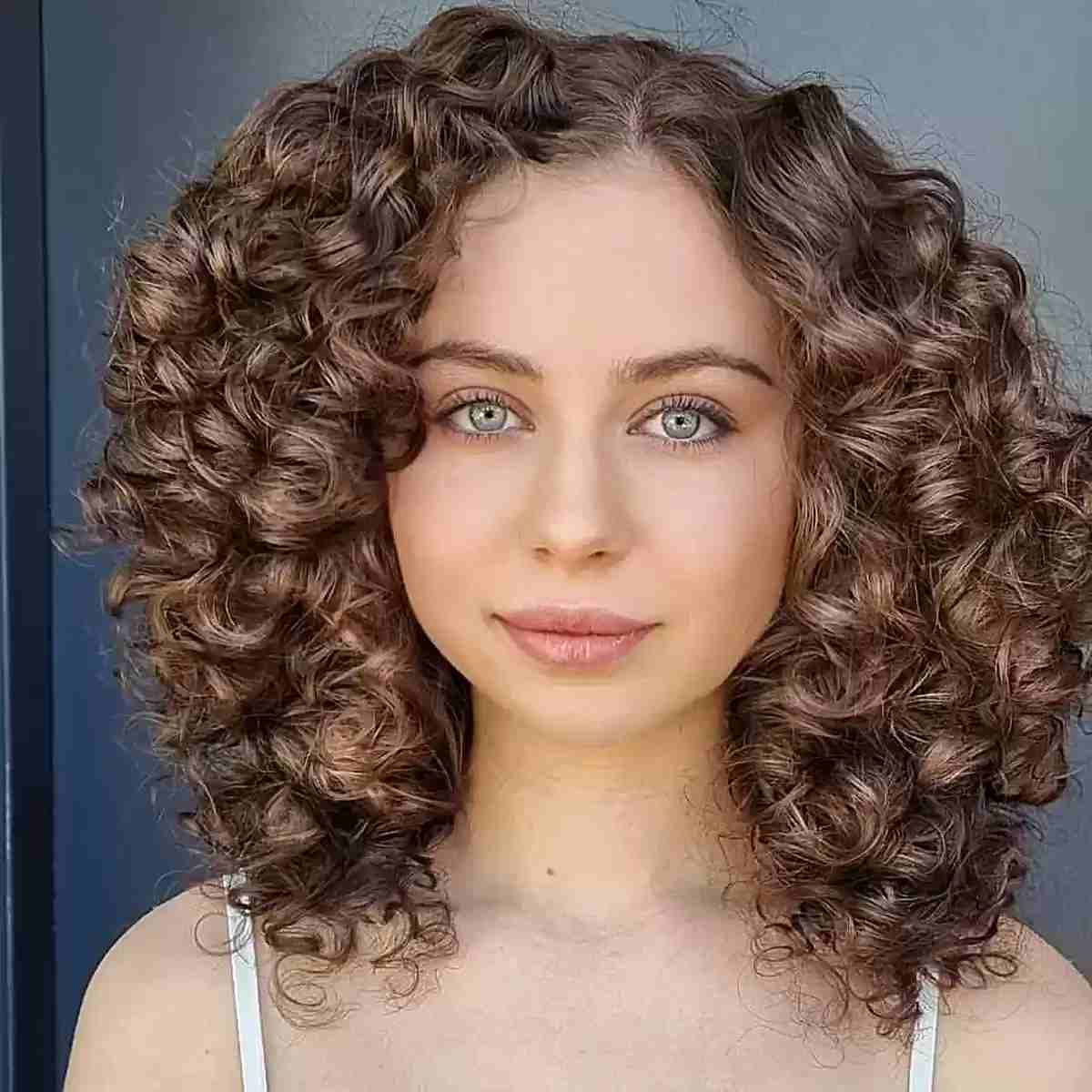 mid length thick curly hair with an off center part