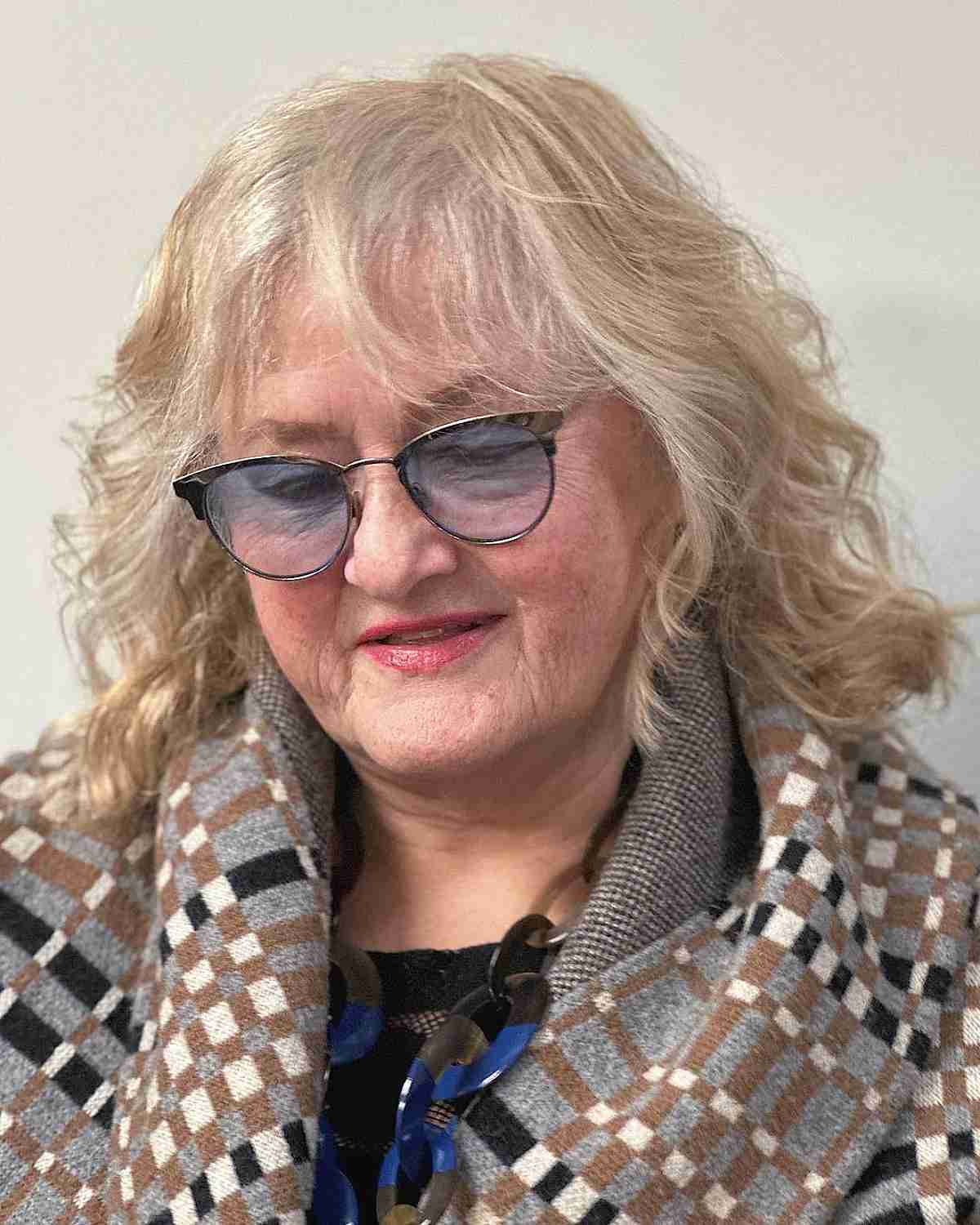 shaggy mid length tousled wavy style with light bangs for women over seventy