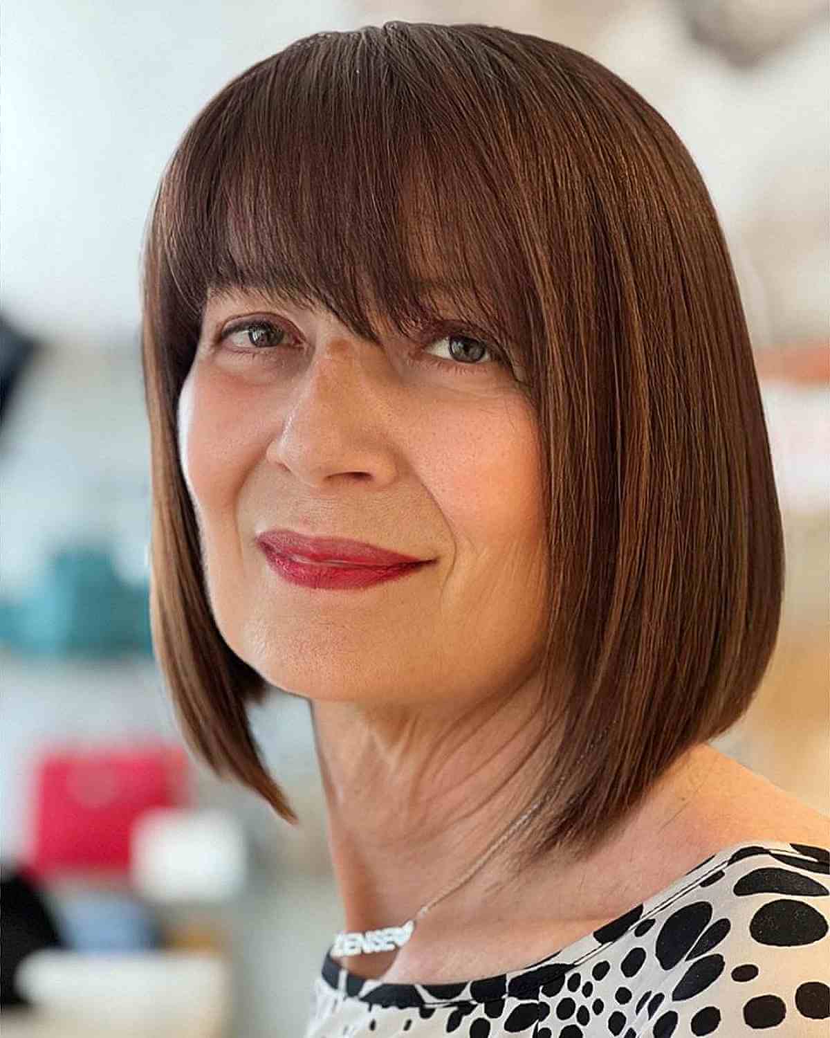 sleek brunette bob with wispy bangs for 50 year old women