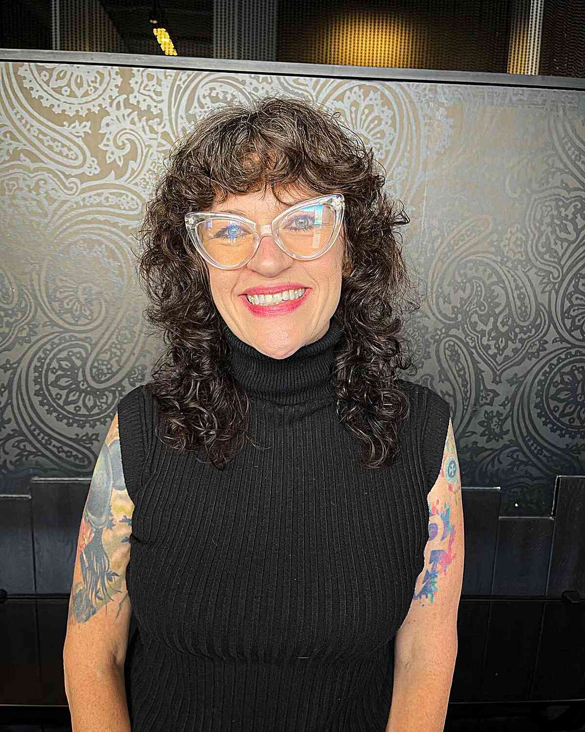 medium length curled shag and bangs for women wearing glasses in their sixties