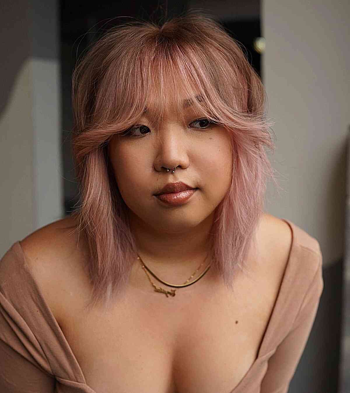 shoulder length pink balayage bob with feathered bangs on ladies with round face shapes
