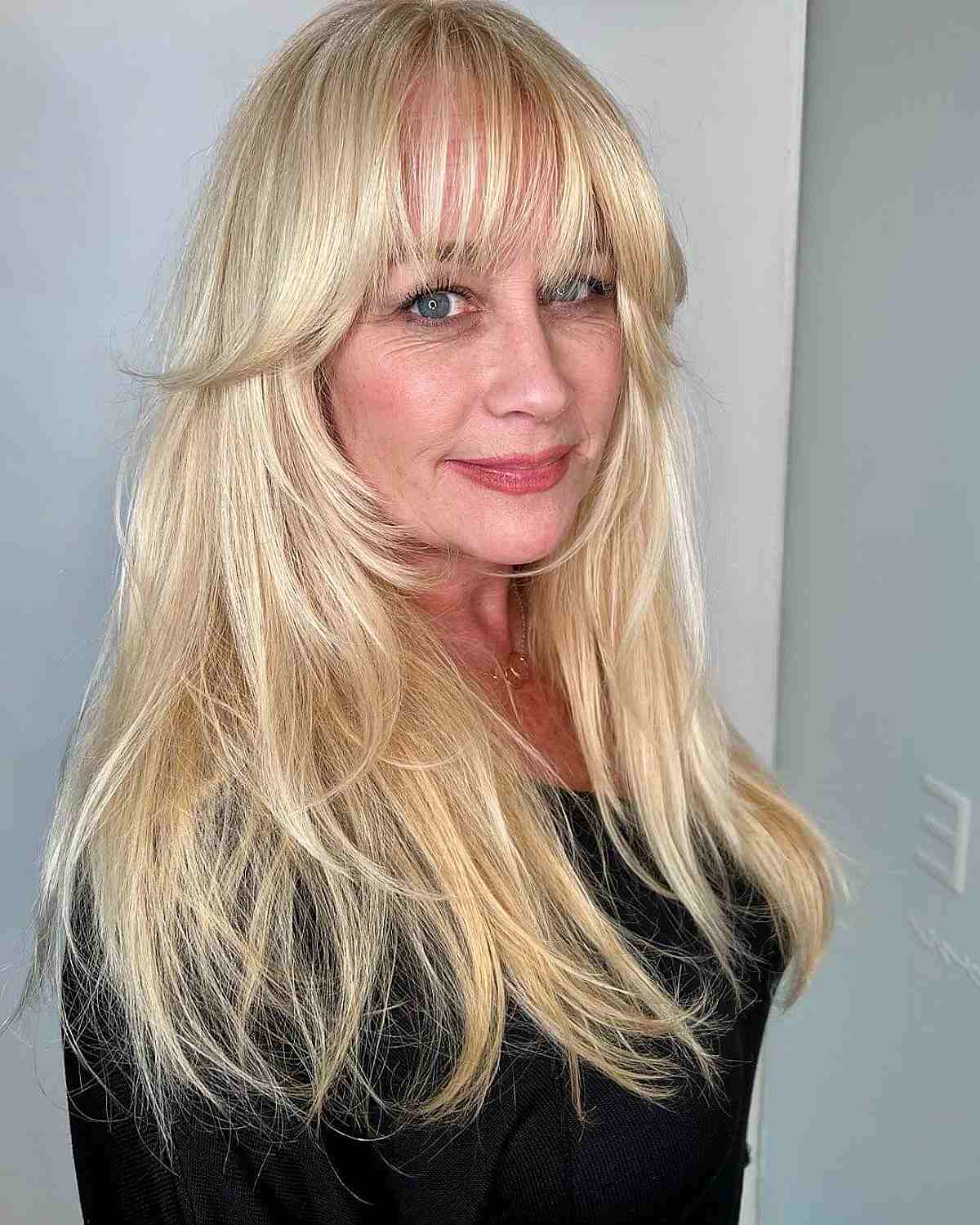 sleek long blonde hair with wispy bangs for ladies 50 and up