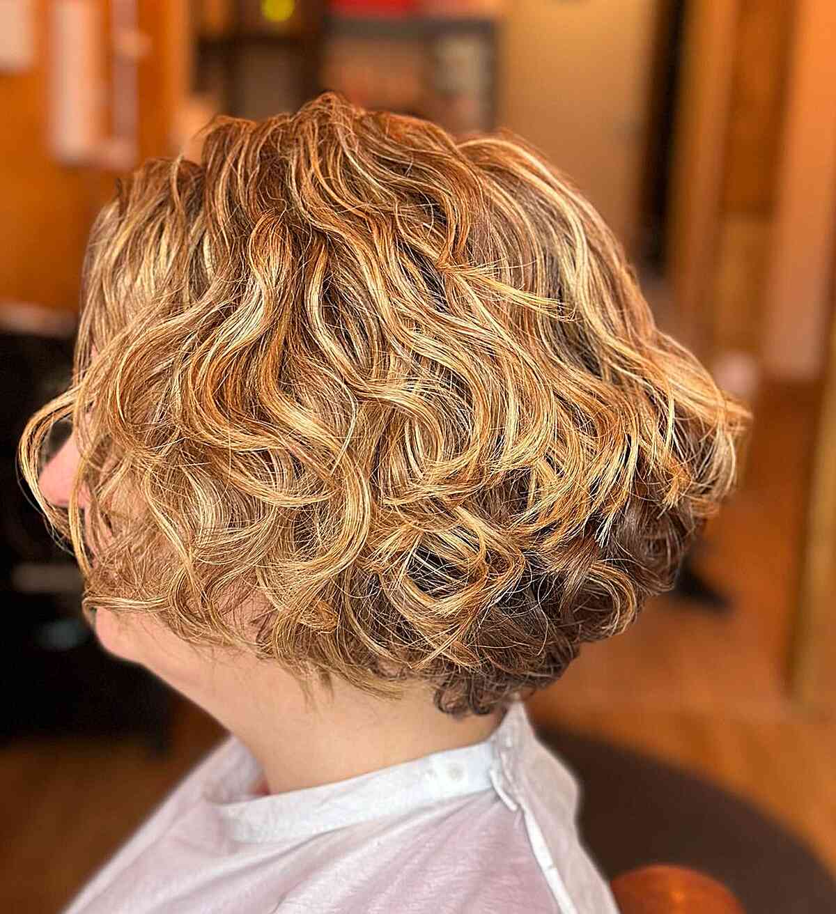 curly blonde bob with graduation for older women