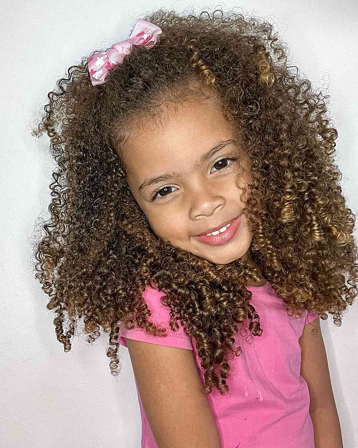 long layered natural curls with pink hair bow for pretty little girls